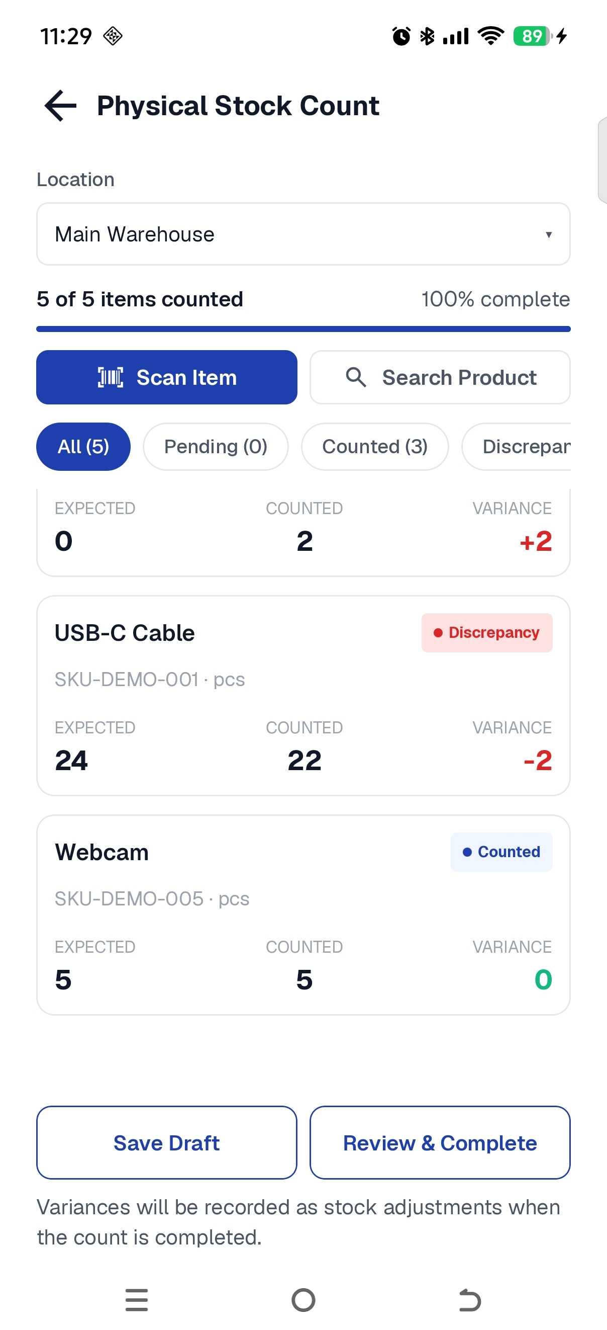 Physical Stock Count screen at Main Warehouse showing 5 of 5 items counted. USB-C Cable is marked Discrepancy with Expected 24, Counted 22 and Variance -2. Webcam is marked Counted with Expected 5, Counted 5 and Variance 0. Save Draft and Review & Complete buttons are visible at the bottom.